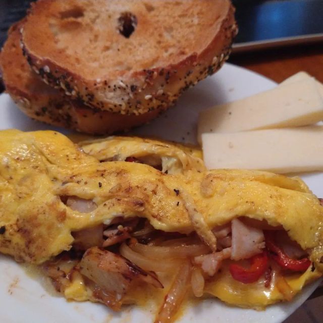 An omelet made with a couple small potatoes #frommygarden with onions, long red pepper (surprisingly spicy!), 1 slice of deli ham cut up and garlic. 1 egg plus heavy cream. Some cheddar cheese. And an everything bagel from @bartsbagels